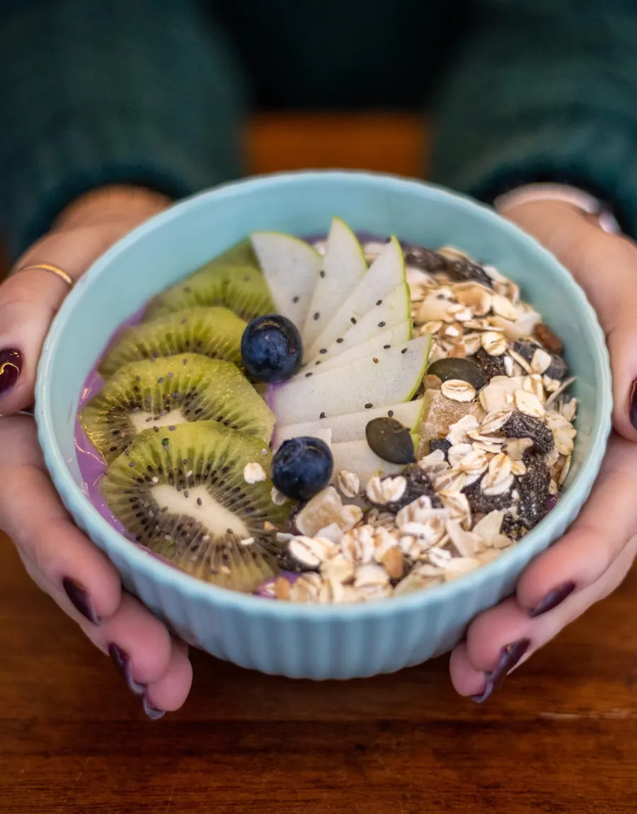 Bowl mit frischem Obst, Joghurt, Kiwi, Heidelbeeren und Müsli